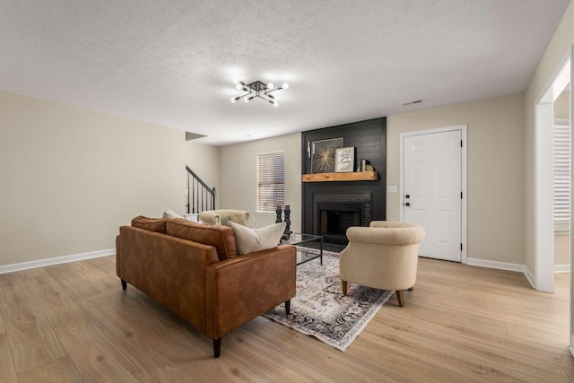 living room featuring a fireplace, light hardwood / wood-style flooring, and a textured ceiling