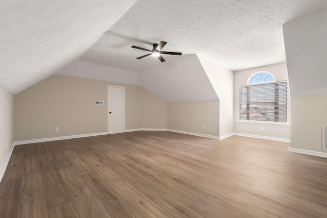 bonus room with ceiling fan, lofted ceiling, hardwood / wood-style floors, and a textured ceiling