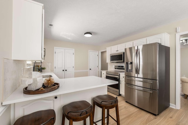 kitchen featuring sink, appliances with stainless steel finishes, a kitchen breakfast bar, white cabinets, and kitchen peninsula