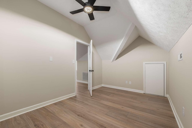 bonus room with hardwood / wood-style flooring, vaulted ceiling, a textured ceiling, and ceiling fan