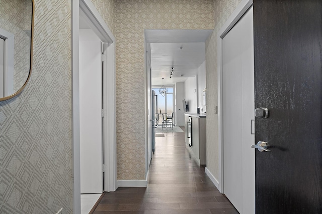 corridor with an inviting chandelier and dark hardwood / wood-style floors