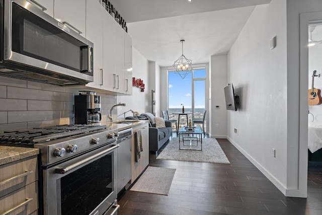 kitchen featuring dark wood-type flooring, white cabinetry, tasteful backsplash, appliances with stainless steel finishes, and pendant lighting