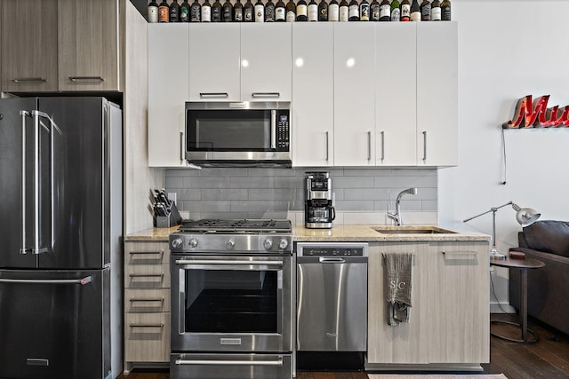 kitchen with white cabinetry, sink, light stone counters, and stainless steel appliances