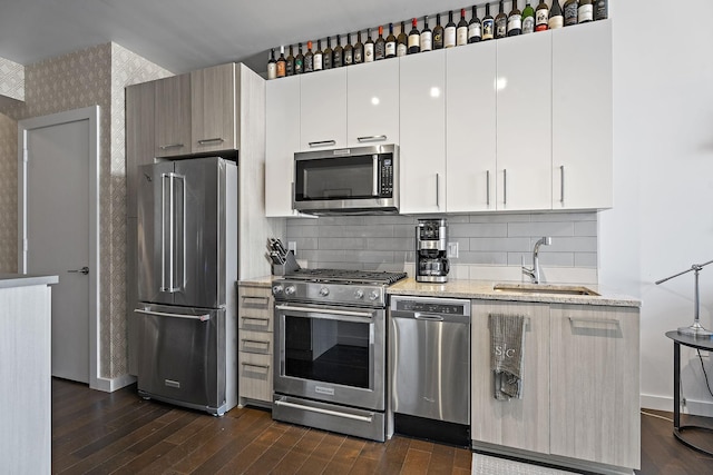 kitchen with appliances with stainless steel finishes, dark hardwood / wood-style flooring, sink, and white cabinets