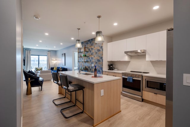 kitchen with sink, white cabinets, stainless steel appliances, a center island with sink, and light hardwood / wood-style flooring