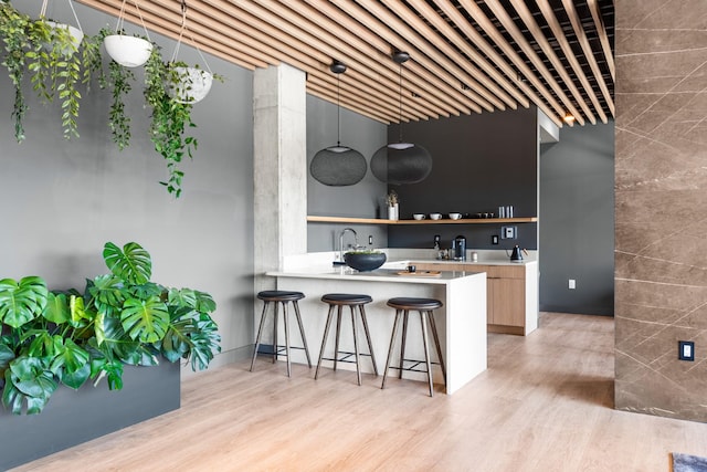 kitchen featuring hanging light fixtures, light hardwood / wood-style flooring, a breakfast bar, and kitchen peninsula