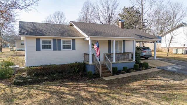 ranch-style house featuring a porch, a carport, and a front yard