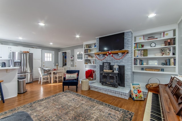 living room featuring ornamental molding, light hardwood / wood-style flooring, and a wood stove