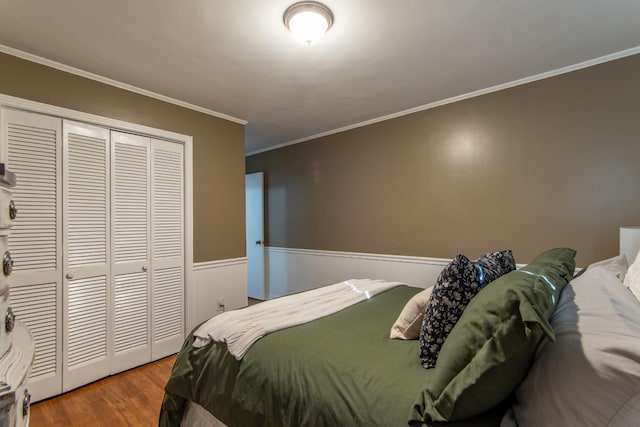 bedroom with hardwood / wood-style flooring, crown molding, and a closet