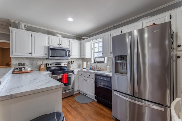 kitchen featuring sink, white cabinets, decorative backsplash, hardwood / wood-style flooring, and stainless steel appliances