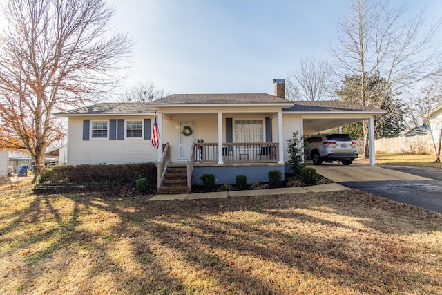 ranch-style home with a front lawn, a carport, and covered porch