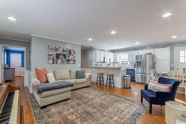 living room featuring crown molding, a wealth of natural light, and light wood-type flooring