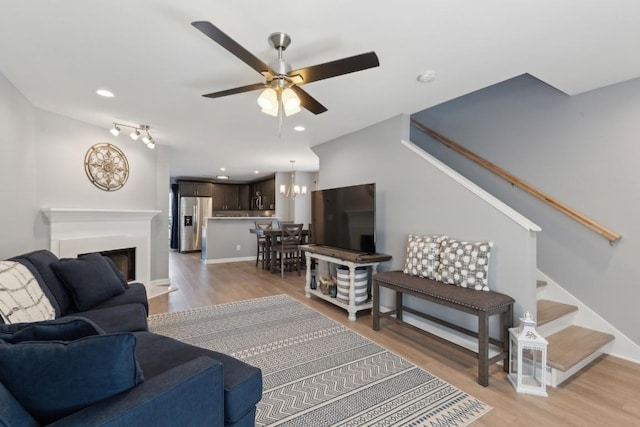 living room featuring wood-type flooring and ceiling fan with notable chandelier