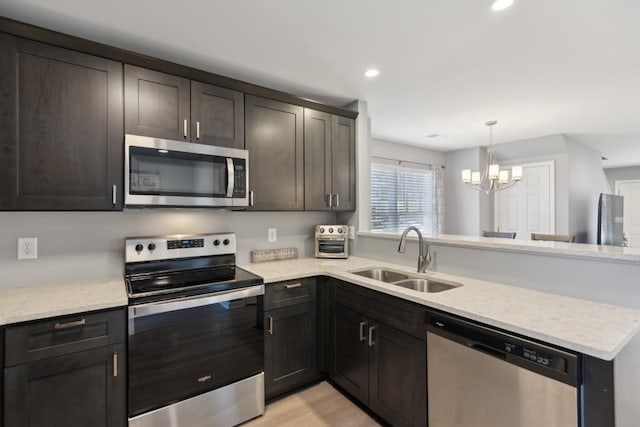 kitchen featuring stainless steel appliances, sink, light stone counters, and dark brown cabinetry