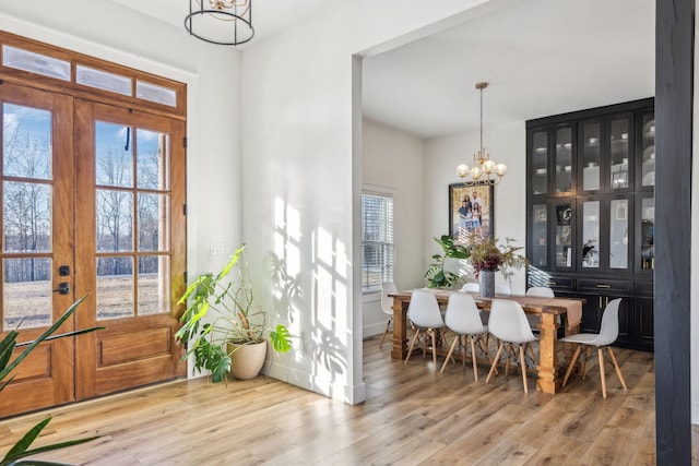 dining space with an inviting chandelier, a healthy amount of sunlight, and light hardwood / wood-style flooring