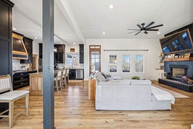 living room featuring a stone fireplace, light wood-type flooring, and a wealth of natural light