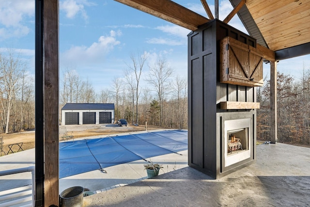 view of pool with exterior fireplace, a garage, and an outdoor structure