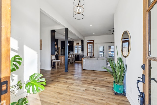 foyer with ceiling fan with notable chandelier and light hardwood / wood-style flooring