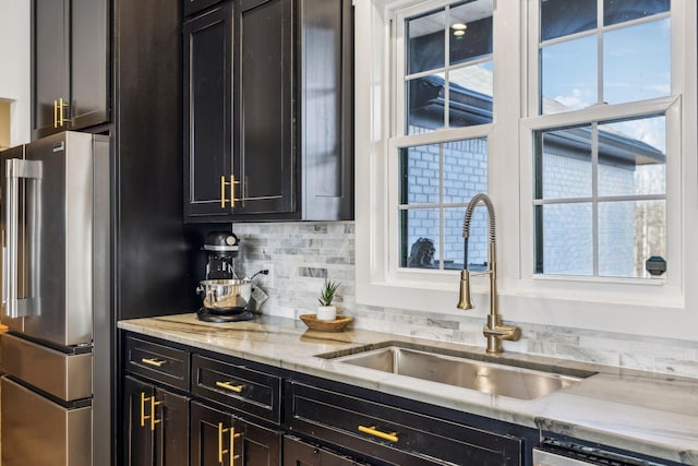 kitchen featuring light stone countertops, appliances with stainless steel finishes, sink, and backsplash