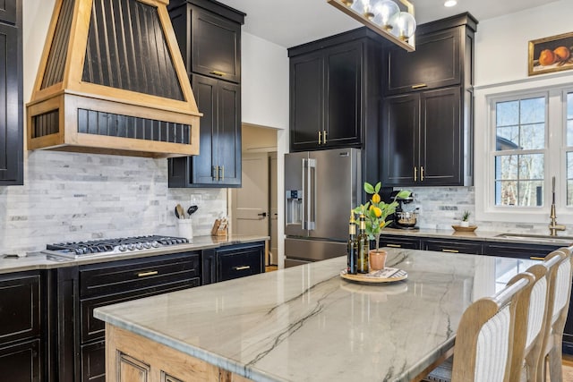 kitchen with sink, appliances with stainless steel finishes, light stone countertops, decorative backsplash, and custom exhaust hood