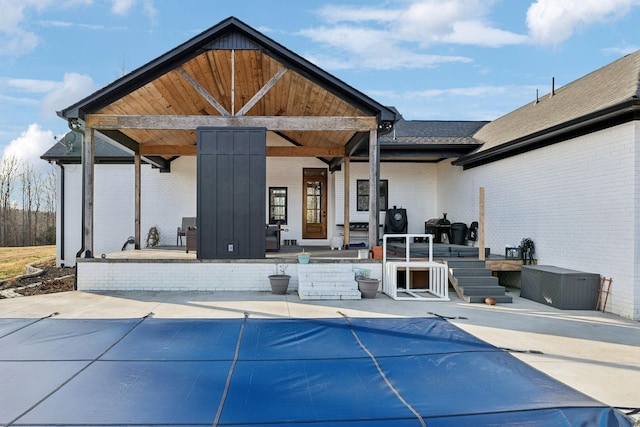 back of property with a patio and a covered pool