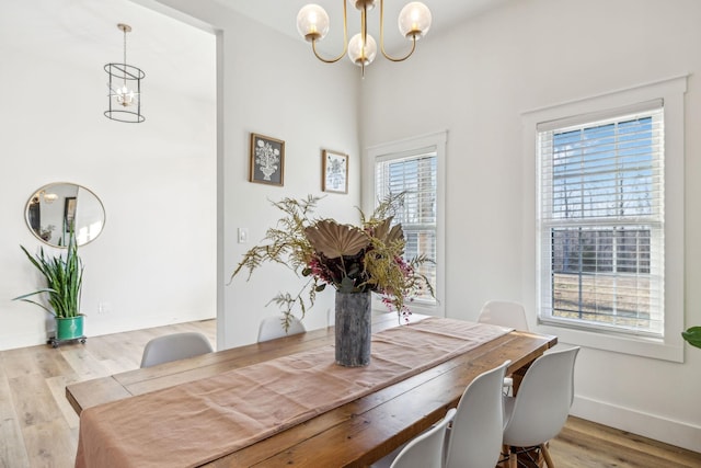 dining area with light hardwood / wood-style flooring and a notable chandelier