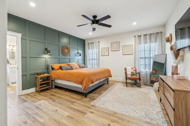 bedroom featuring ensuite bathroom, ceiling fan, and light wood-type flooring