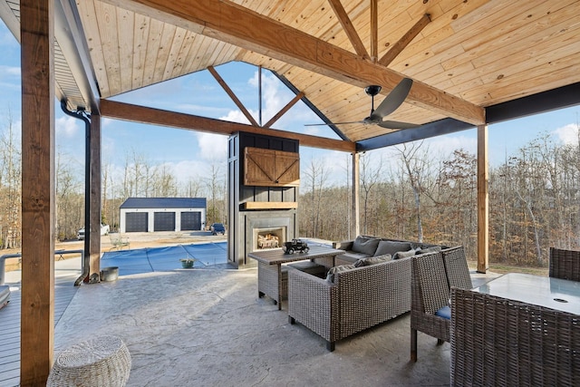 view of patio with an outdoor living space with a fireplace, a covered pool, and an outbuilding