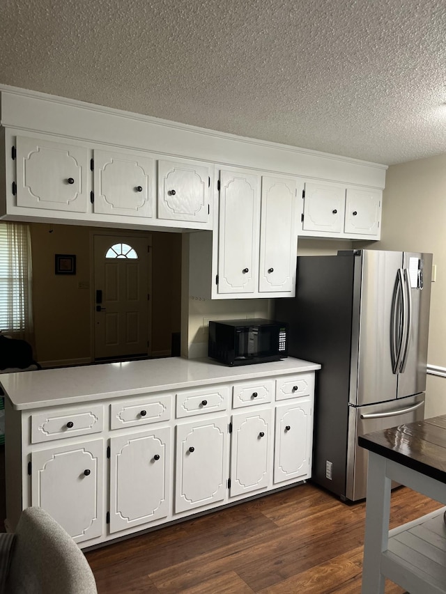 kitchen featuring dark hardwood / wood-style flooring, a textured ceiling, stainless steel refrigerator, and white cabinets