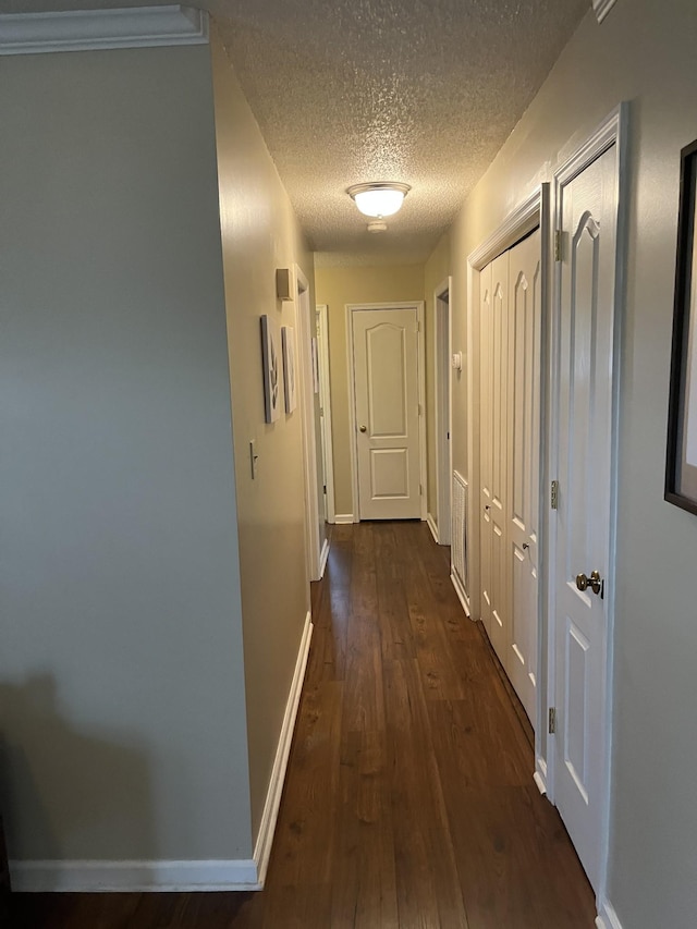 hall with dark hardwood / wood-style flooring and a textured ceiling