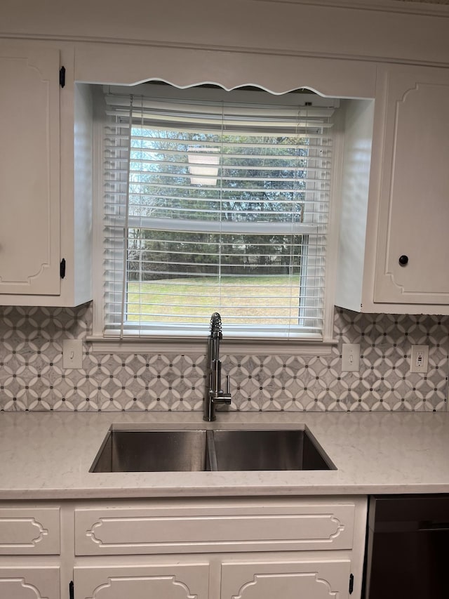 kitchen with black dishwasher, sink, decorative backsplash, and white cabinets