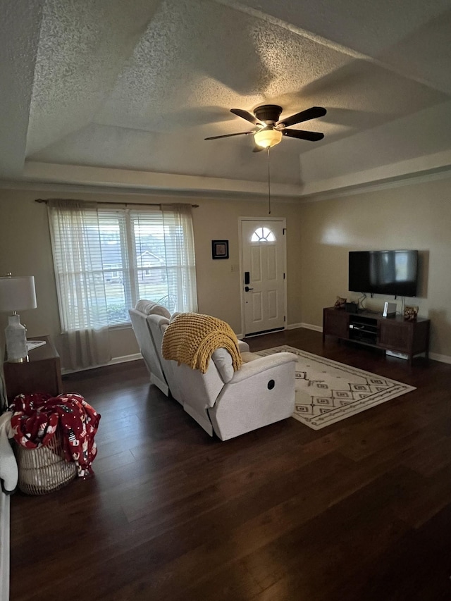 living room with dark hardwood / wood-style floors, ceiling fan, a tray ceiling, and a textured ceiling