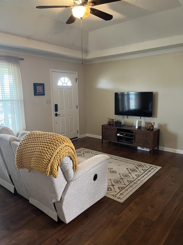 living room with dark wood-type flooring, a textured ceiling, ceiling fan, and a tray ceiling