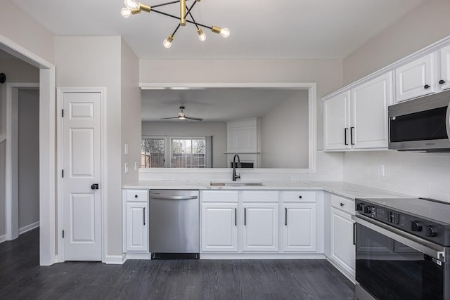 kitchen featuring appliances with stainless steel finishes, tasteful backsplash, white cabinetry, sink, and dark wood-type flooring