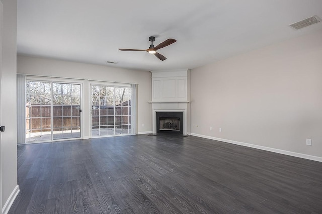 unfurnished living room with ceiling fan, a large fireplace, and dark hardwood / wood-style flooring