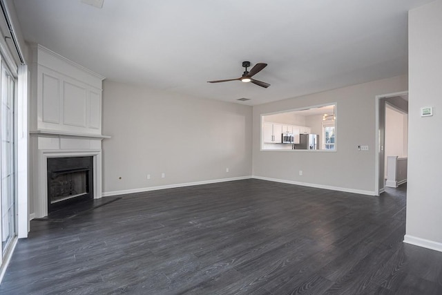 unfurnished living room with dark wood-type flooring, a fireplace, and ceiling fan