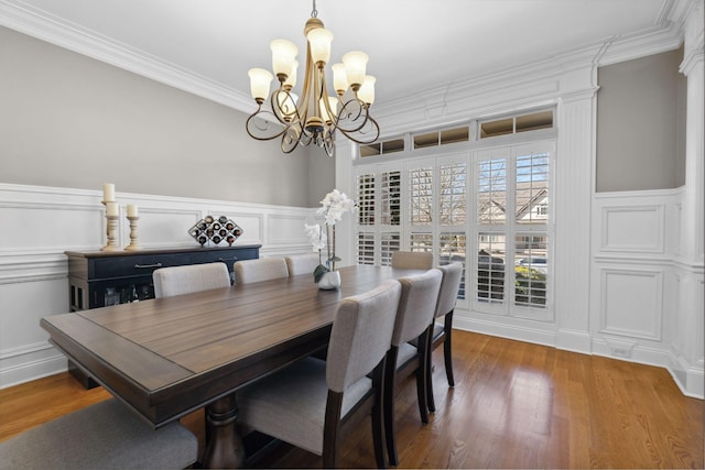 dining room with hardwood / wood-style flooring, ornamental molding, and an inviting chandelier