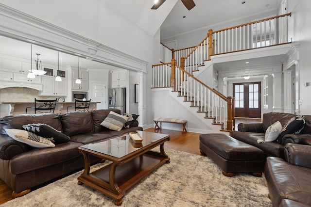 living room with french doors, ornamental molding, dark hardwood / wood-style floors, ceiling fan, and a high ceiling