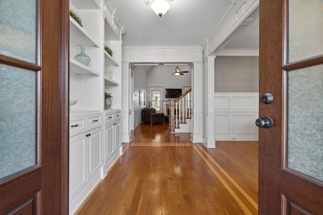 interior space featuring hardwood / wood-style flooring, ornamental molding, and decorative columns