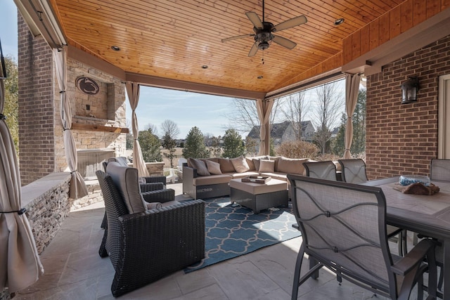 view of patio / terrace featuring ceiling fan and an outdoor living space with a fireplace