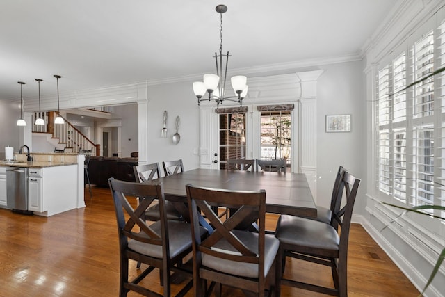 dining area featuring ornamental molding, sink, a notable chandelier, and dark hardwood / wood-style floors