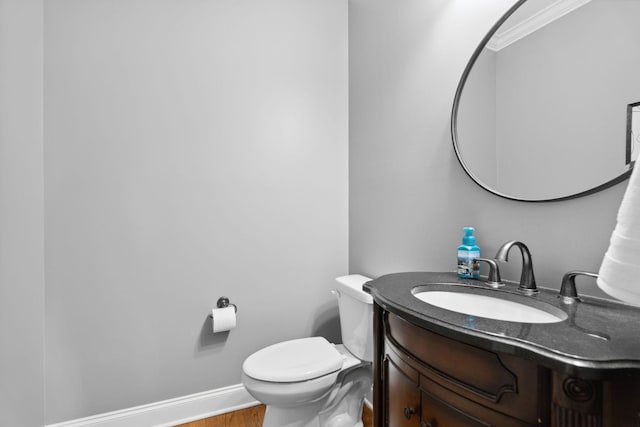 bathroom featuring vanity, hardwood / wood-style floors, ornamental molding, and toilet