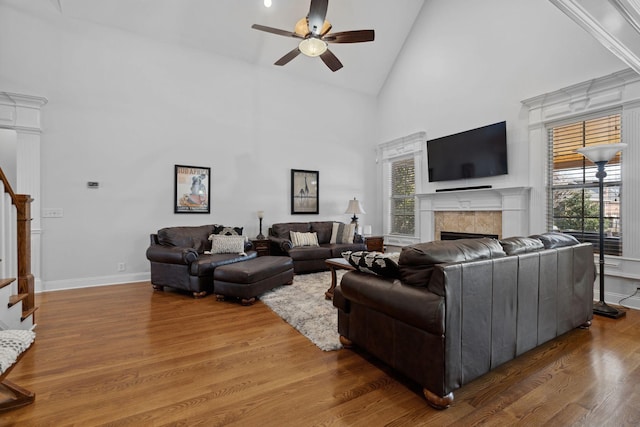 living room featuring a tiled fireplace, ceiling fan, hardwood / wood-style floors, and high vaulted ceiling