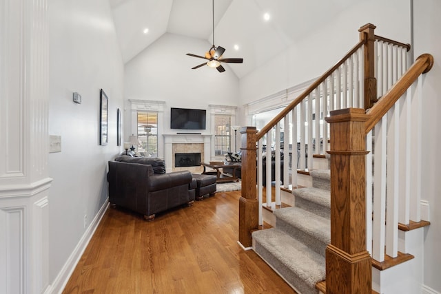 living room featuring ceiling fan, high vaulted ceiling, and light hardwood / wood-style flooring