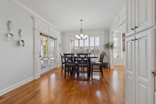 dining room with crown molding, hardwood / wood-style floors, and an inviting chandelier