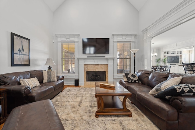 living room with a fireplace, high vaulted ceiling, and ornate columns