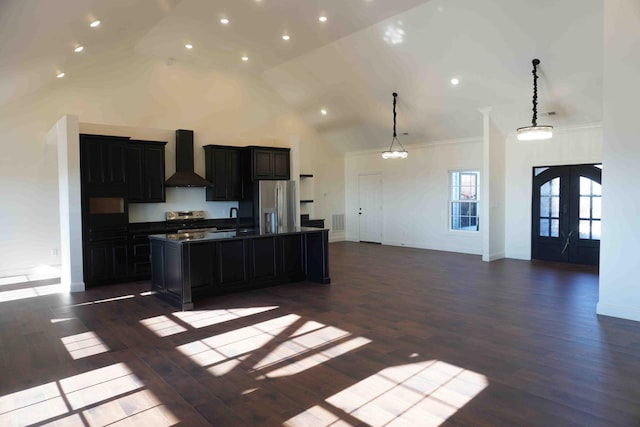 kitchen featuring french doors, a center island with sink, stainless steel appliances, open floor plan, and wall chimney range hood