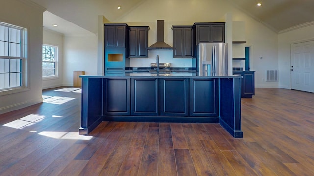 kitchen featuring a center island with sink, visible vents, appliances with stainless steel finishes, ornamental molding, and wall chimney exhaust hood