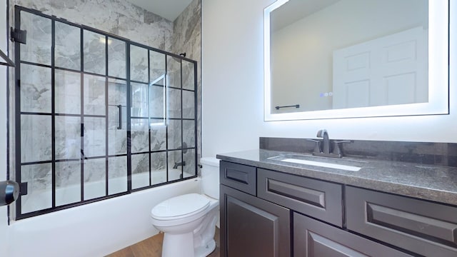 bathroom with bath / shower combo with glass door, vanity, and toilet