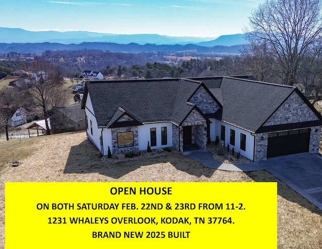 view of front facade featuring stone siding, driveway, an attached garage, and a mountain view